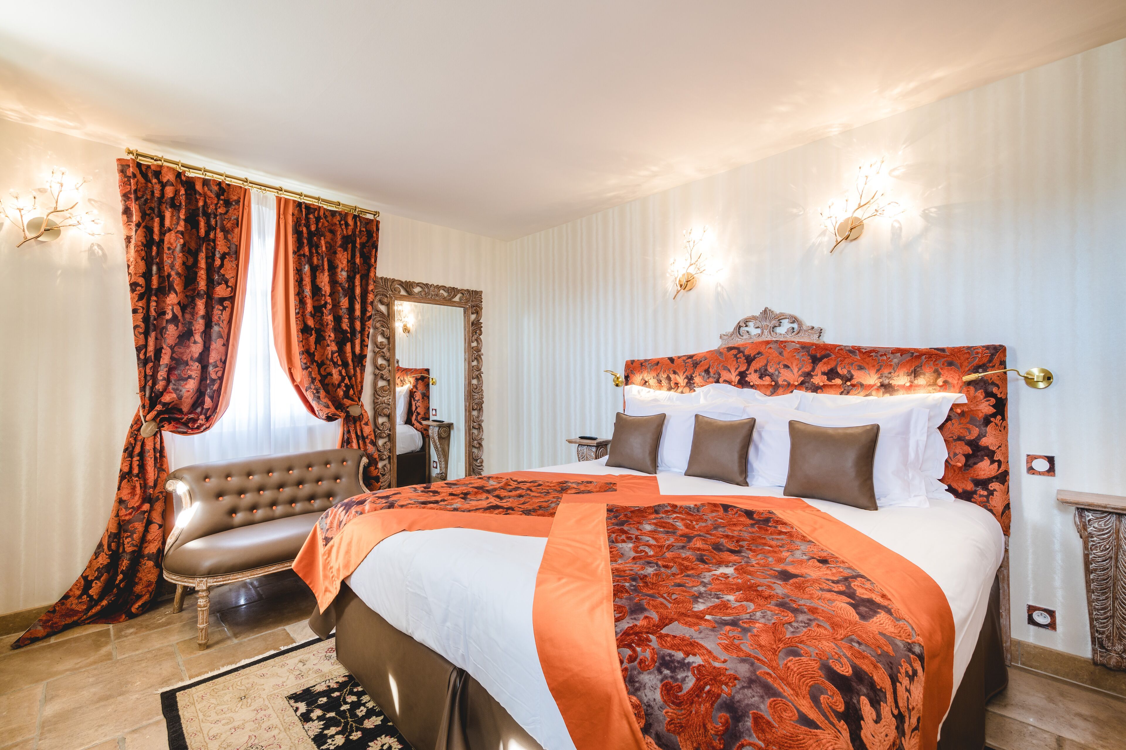A spacious bedroom with a large bed, a vanity with a mirror, and a seating area with a sofa.