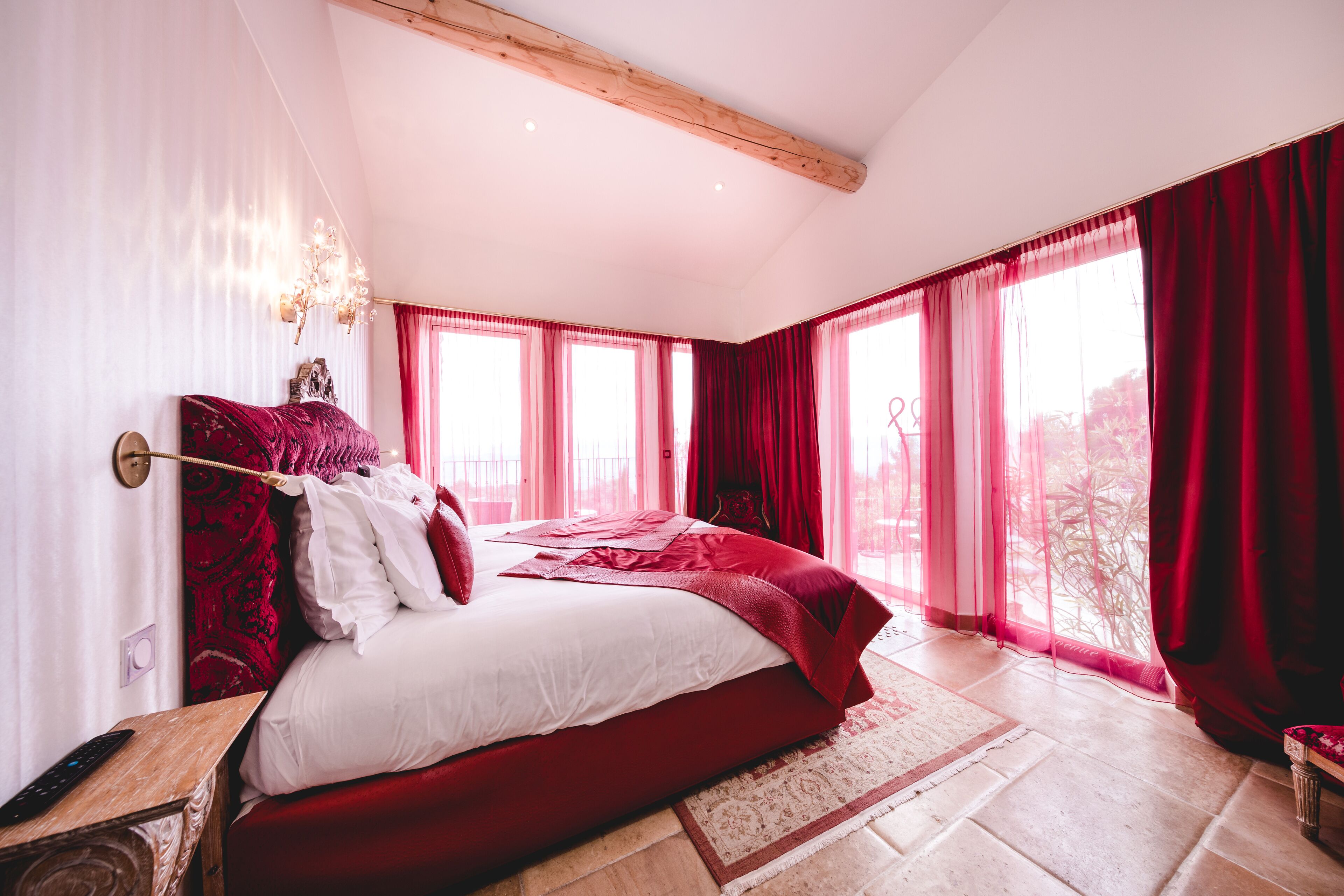 Un dormitorio con una cama grande, cortinas rojas y un candelabro.