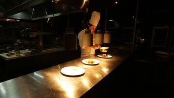 Un chef preparando comida en una cocina luminosa con superficies de acero inoxidable y equipo moderno.