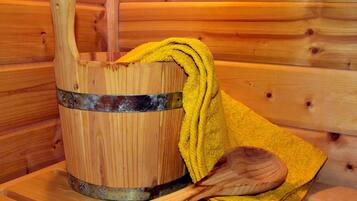 A wooden bucket with a metal band, a yellow towel, and a wooden spoon on a wooden surface.