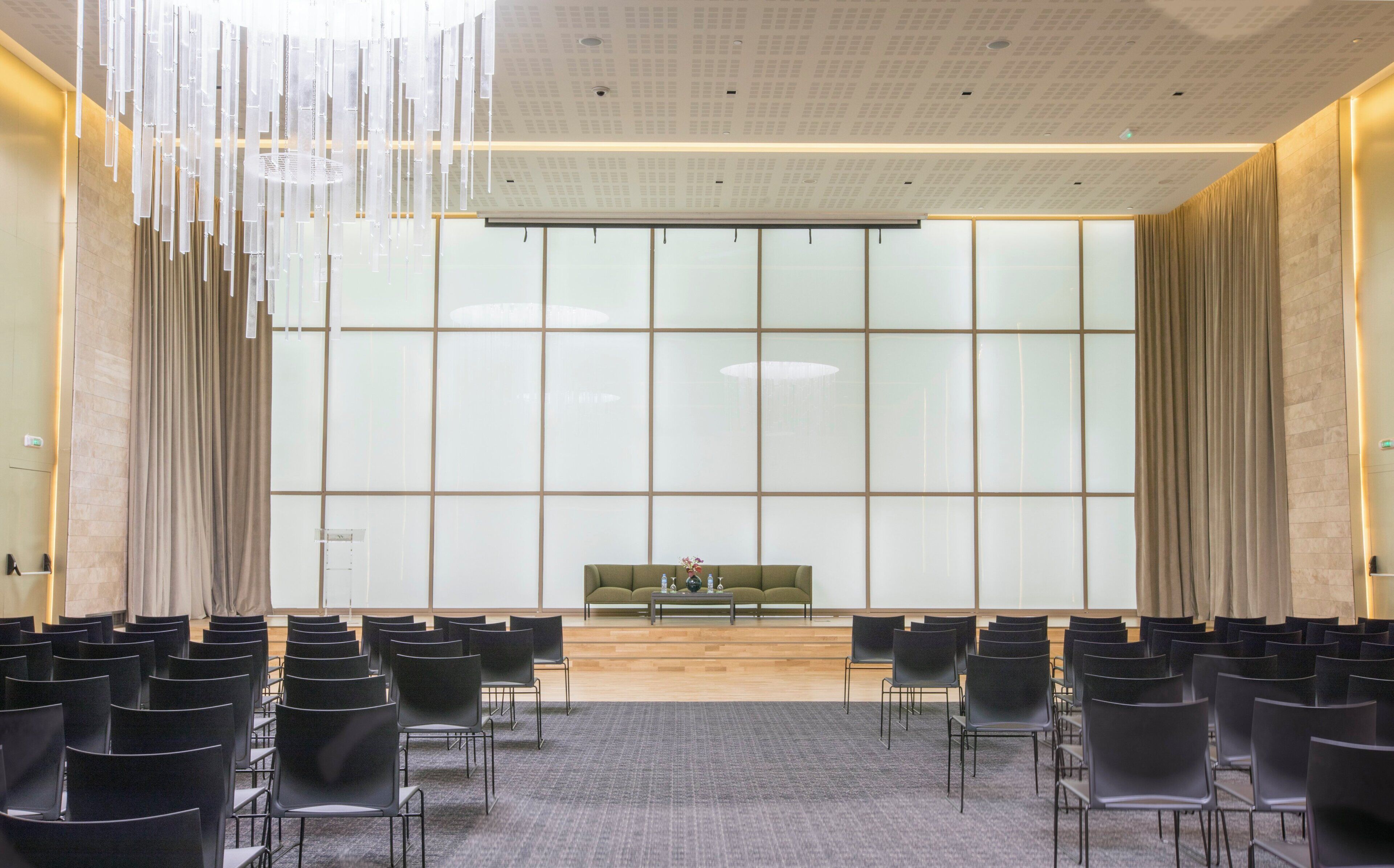 Une salle de conférence avec une longue table, des chaises et une grande fenêtre avec des rideaux.
