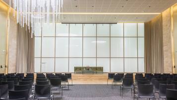 A conference room with a long table, chairs, and a large window with curtains.