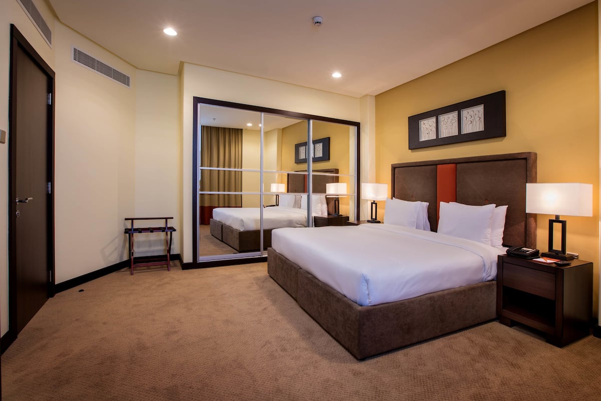 Une chambre d’hôtel avec un grand lit, une table de chevet avec une lampe, un miroir et un tableau accroché au mur.