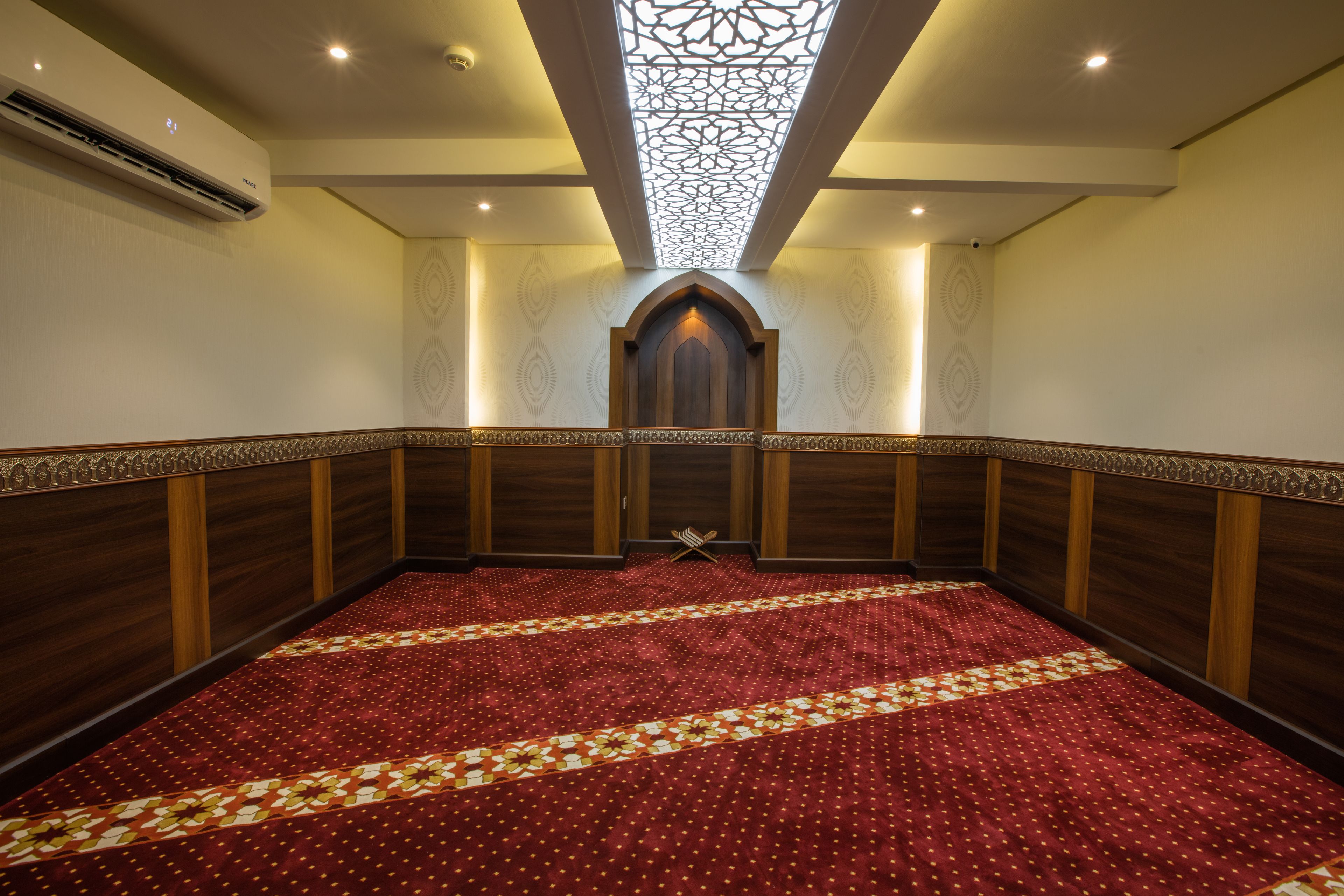 A large, carpeted room with a patterned floor, wooden paneling, and a skylight.