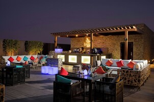 Un'area salotto all'aperto con mobili in vimini e un bar sullo sfondo.