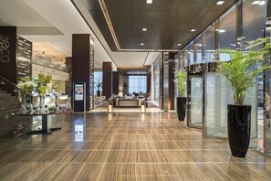 A modern lobby with a reception desk, seating area, and large potted plants. - Rosh Olaya Hotel (Riyadh)
