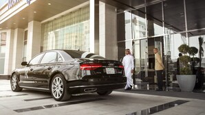A black luxury car parked in front of a hotel with a glass facade and a sign reading "Kosh Rayhaan by Rotana". - Rosh Olaya Hotel (Riyadh)