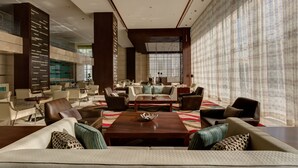 A spacious lobby with multiple seating areas, a central coffee table, and a large window with patterned curtains. - Rosh Olaya Hotel (Riyadh)