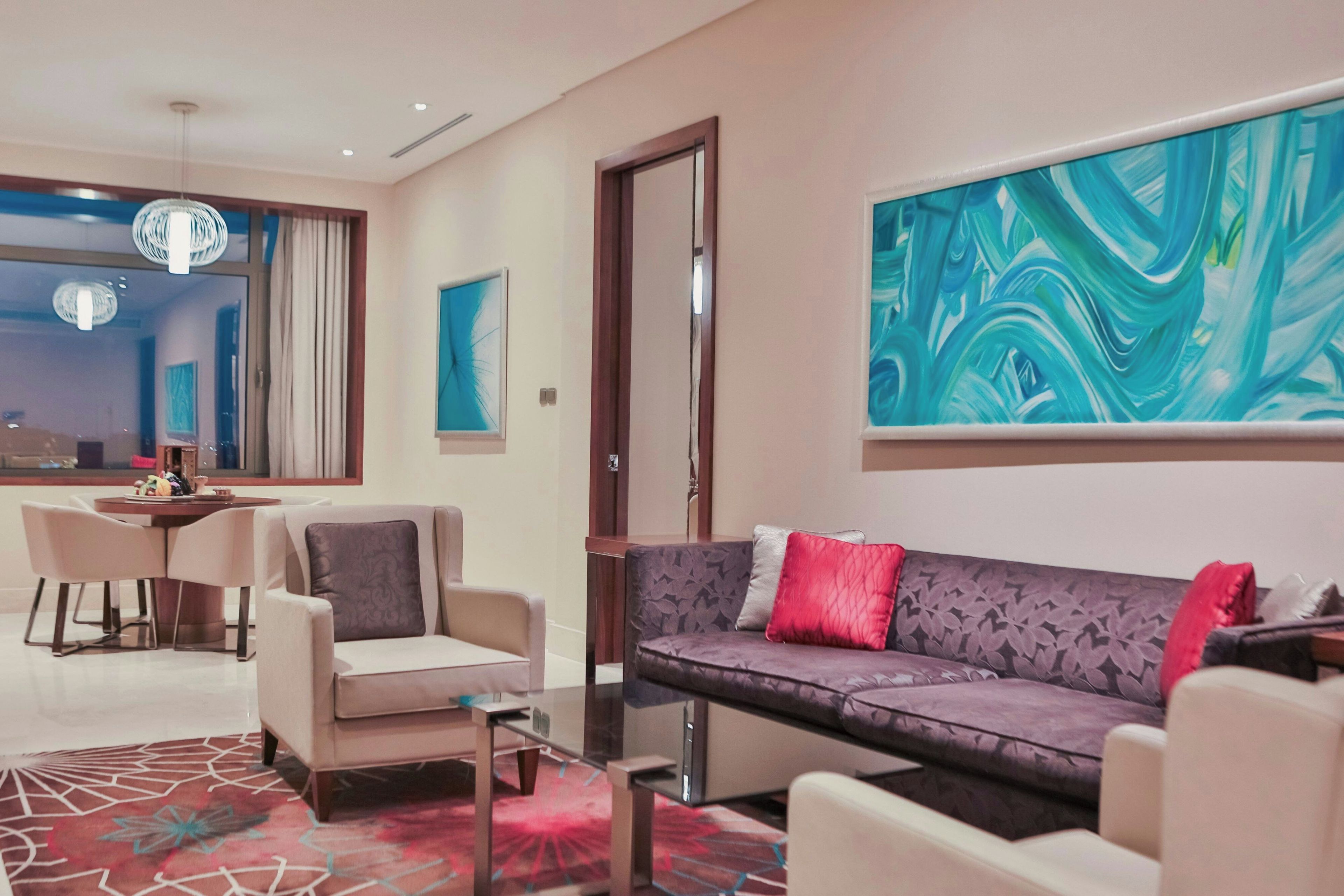 A modern living room with a sofa, armchairs, a coffee table, and a dining area with a table and chairs.