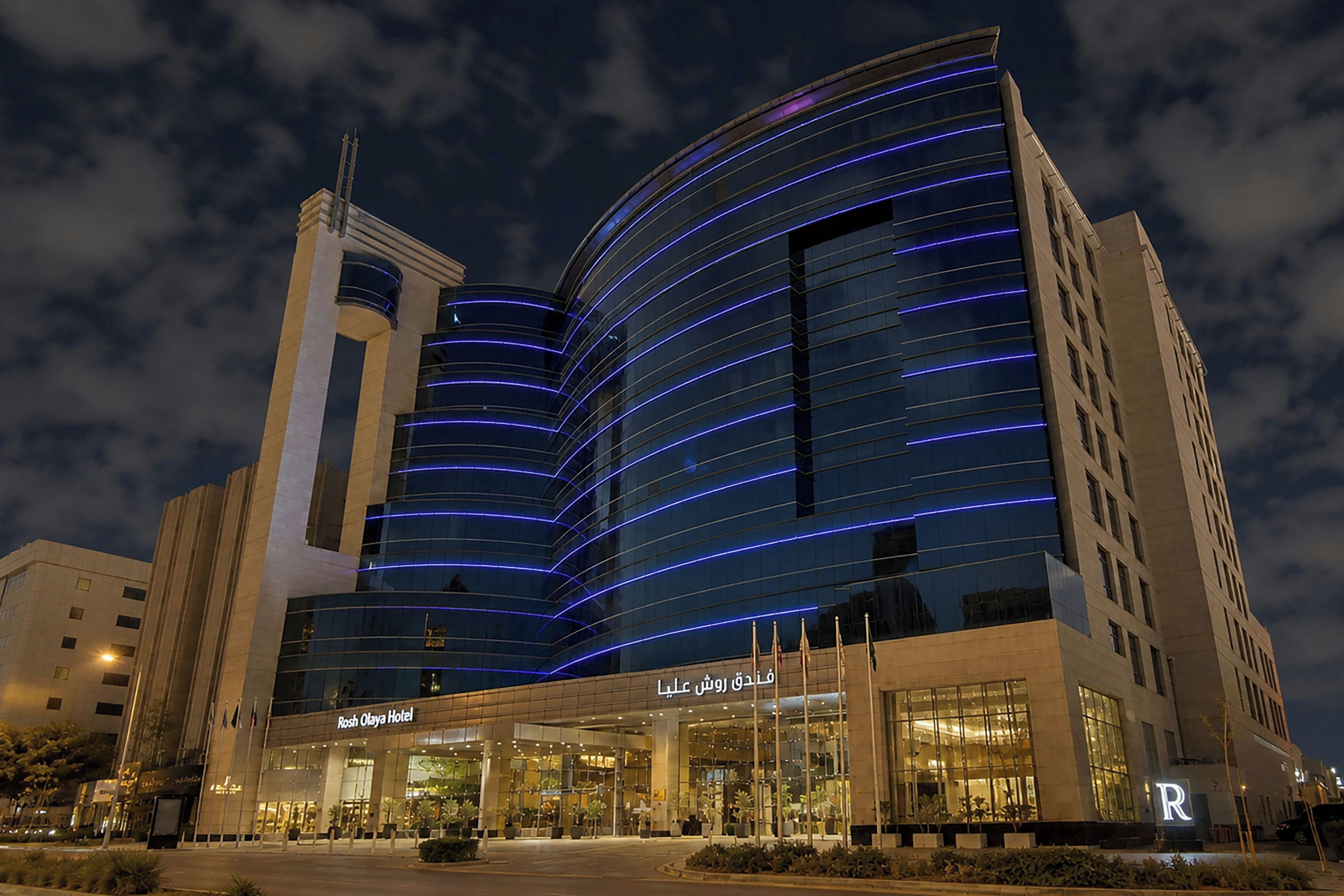 A modern hotel with a curved glass facade and a prominent entrance.