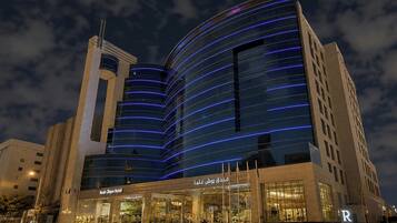A modern hotel with a curved glass facade and a prominent entrance.