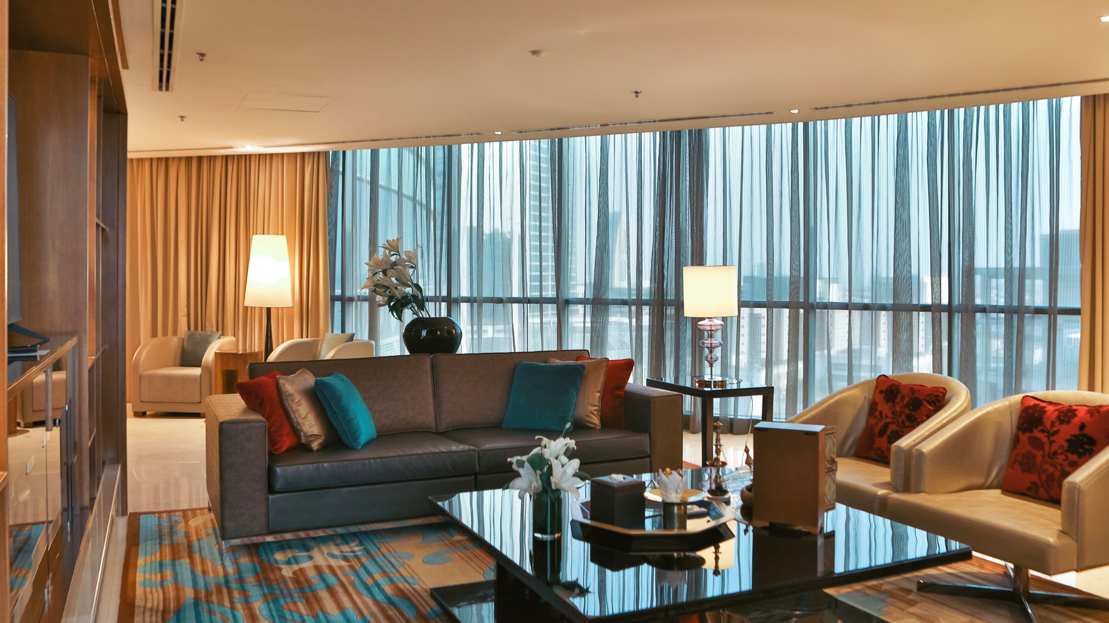 Une chambre d’hôtel moderne avec une grande fenêtre, un canapé, une table basse et un fauteuil.