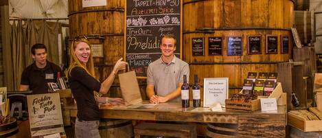 Un espace dédié à la dégustation de vins, avec des barriques en bois, un tableau noir servant de menu et un panneau indiquant « Tappit-Hen n° 30, saveur automnale ».