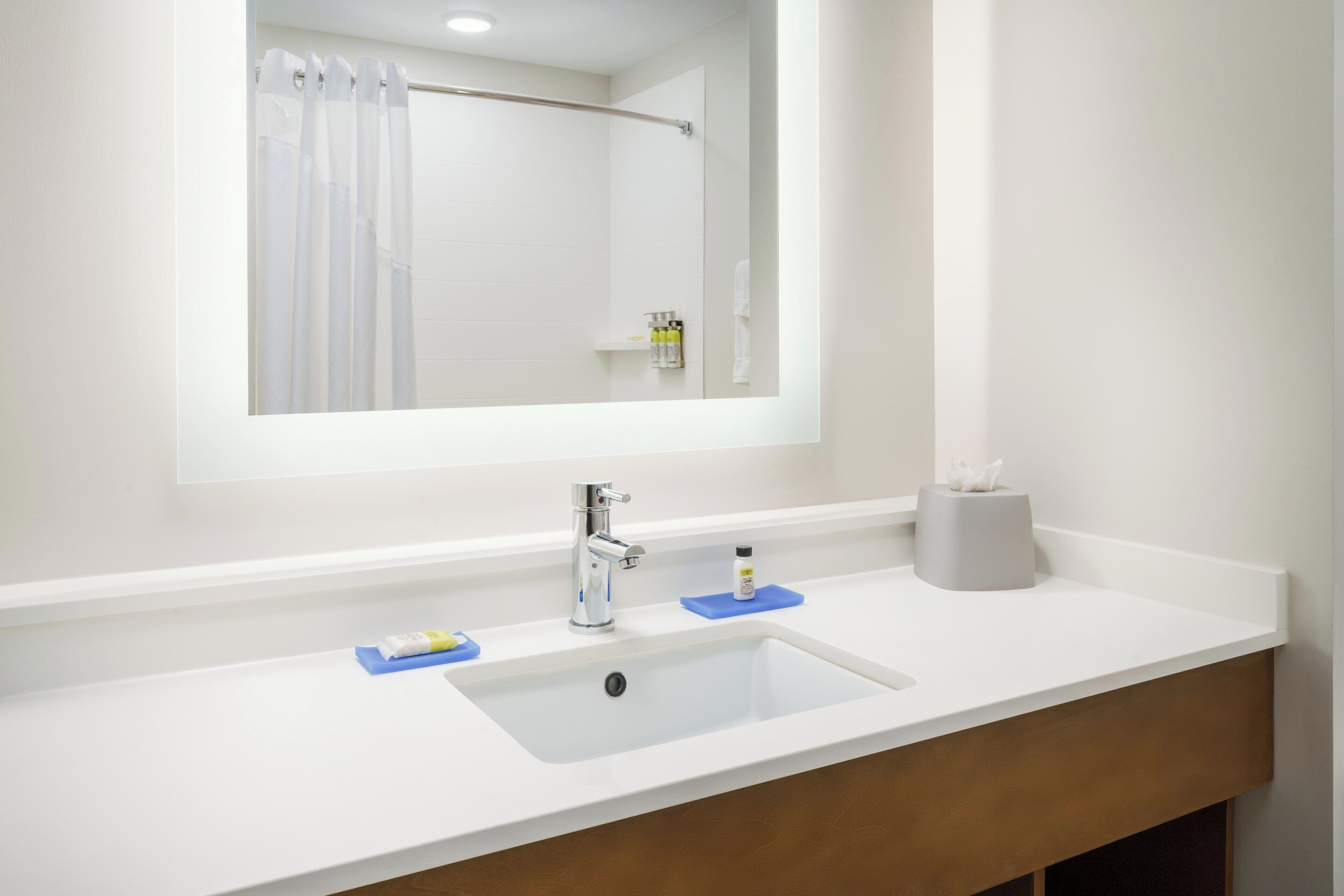 A bathroom with a white sink, a mirror, and a shower curtain.