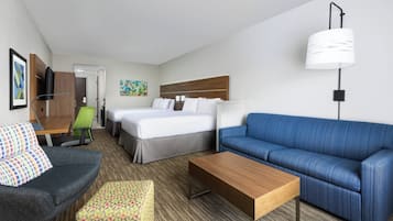 Una habitación de hotel con cama, sofá, escritorio, silla y televisión.