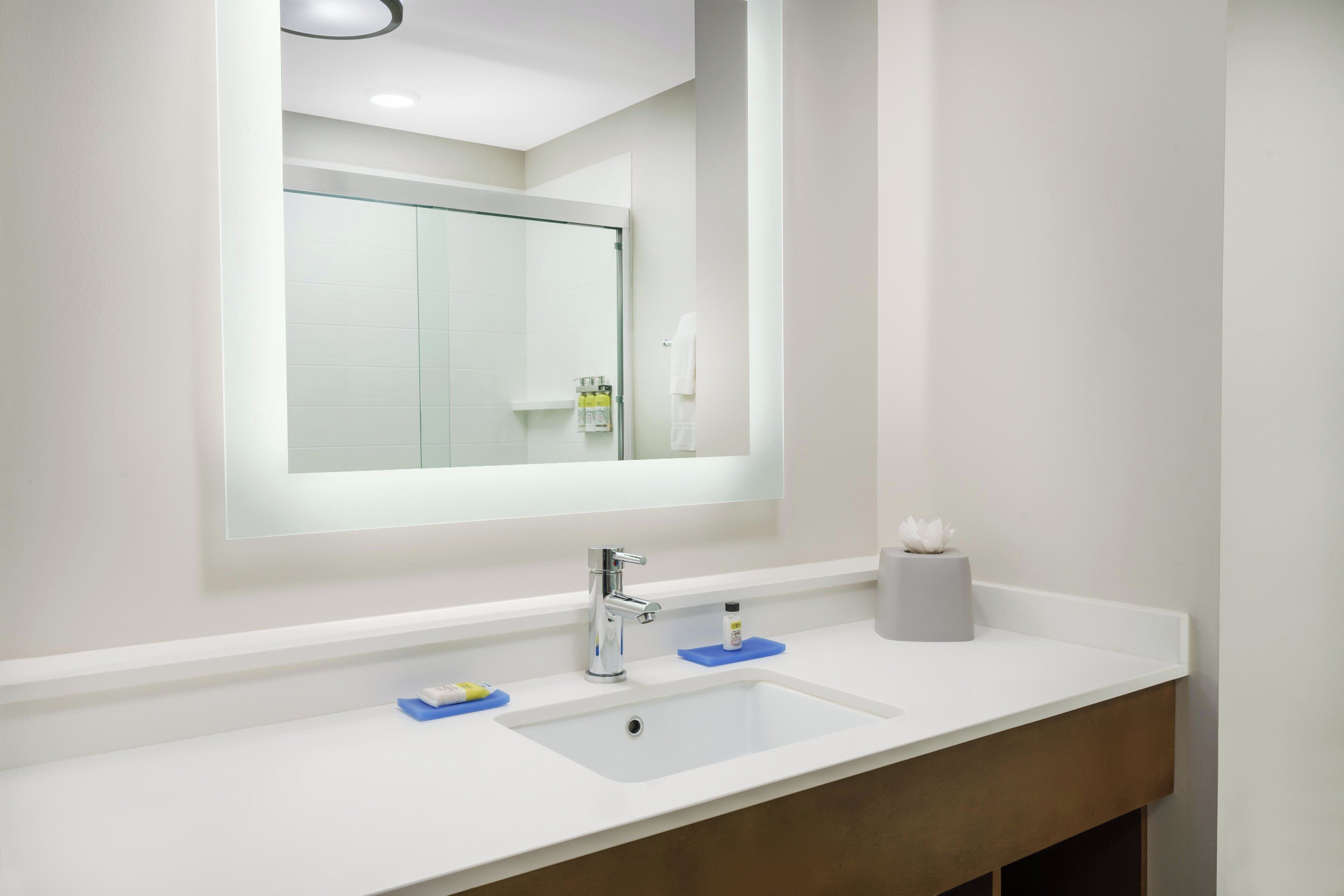 A modern bathroom with a white sink, a mirror, and a toilet.