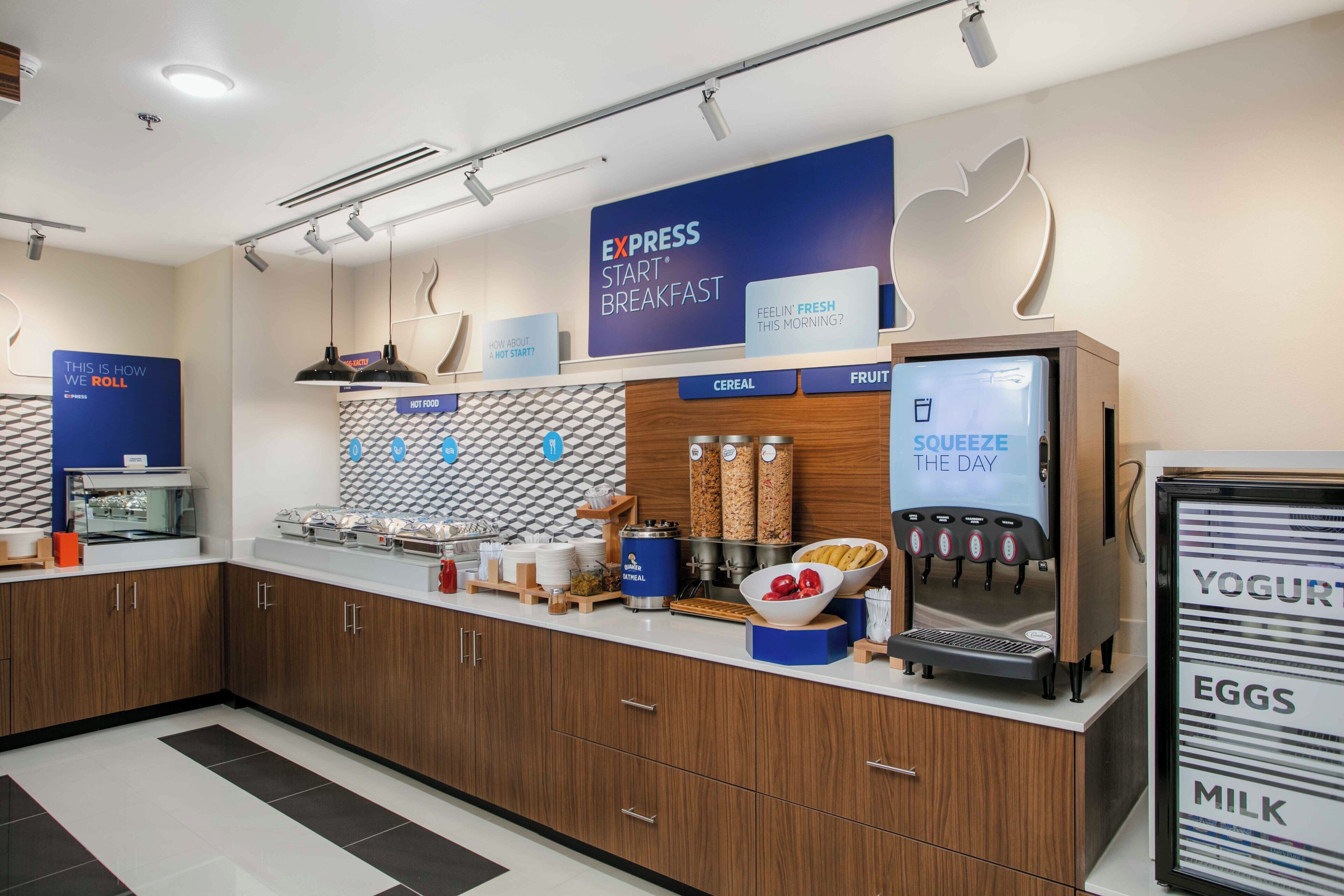 Una moderna area colazione con un cartello che dice 'EXPRESS START BREAKFAST' e proposte di cereali, frutta e yogurt.