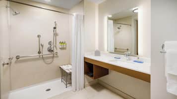 A modern bathroom with a walk-in shower, a bathtub, a vanity with a mirror, and a towel rack.