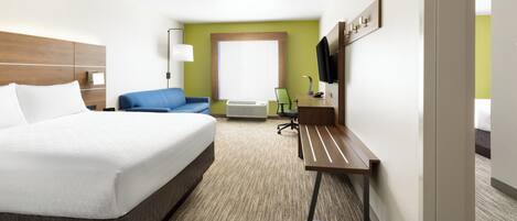 A hotel room with a bed, a desk, a chair, a TV, and a window.