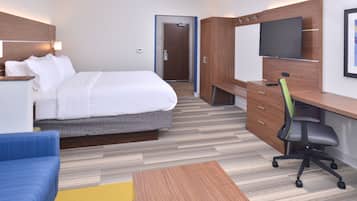 A hotel room with a bed, a desk with a chair, a TV, and a wardrobe.