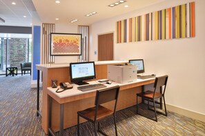A reception desk with two computer monitors, a phone, and a keyboard. There are two chairs in front of the desk. - Holiday Inn Express & Suites Omaha Airport by IHG (Carter Lake)