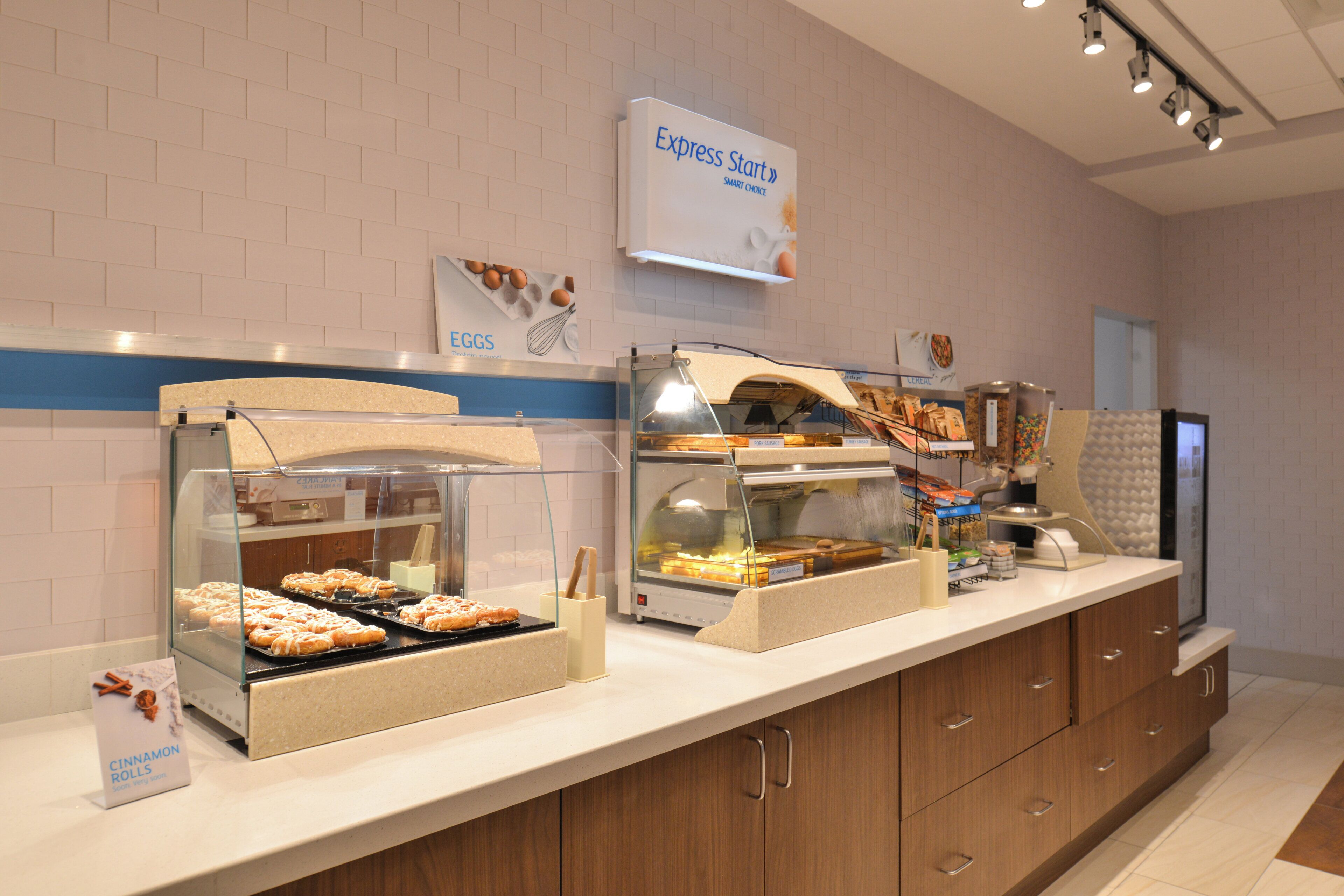 Un bufé de desayuno con diversas opciones de comida, como huevos y pasteles, en un ambiente moderno con un diseño limpio.
