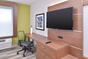 Un espacio de oficina moderno con un escritorio de madera, una silla de oficina verde, un televisor montado y una obra de arte abstracta enmarcada en la pared.