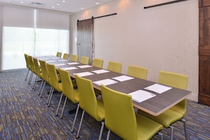 A conference room with a long table, yellow chairs, and a patterned carpet. - Holiday Inn Express & Suites Omaha Airport by IHG (Carter Lake)
