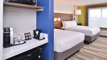 A hotel room with a minibar, a bed, a desk, and a window.