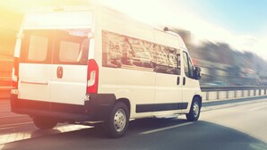 Ein weißer Lieferwagen fährt auf einer Autobahn.