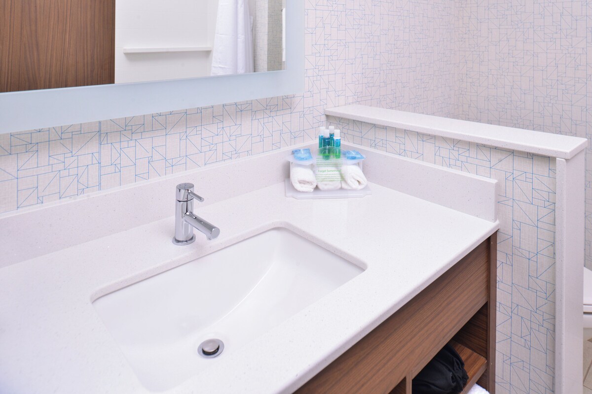 Un baño con un lavamanos blanco, un espejo y un dispensador de toallas.