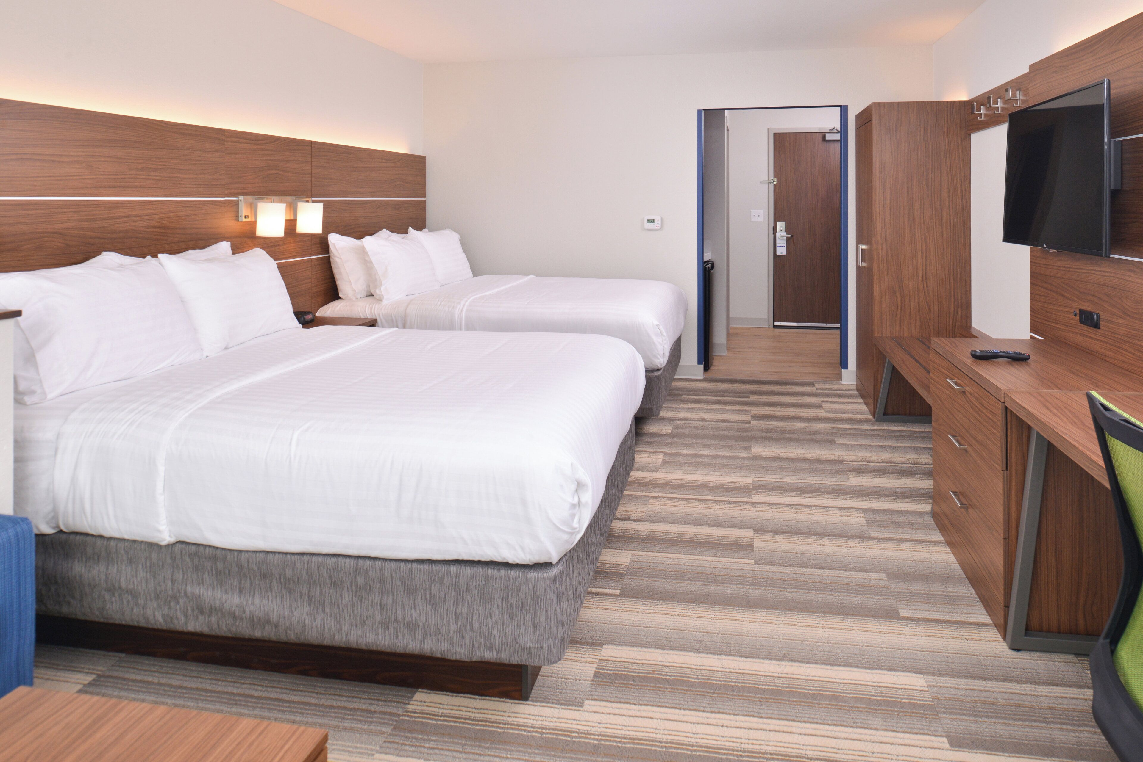 A hotel room with two beds, a TV, a desk, and a wardrobe.