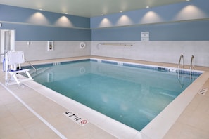 An indoor swimming pool with clear water, marked depth lines, and a no diving sign.