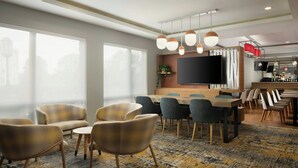 Una habitación de hotel moderna con un ventanal grande, una zona de comedor con bar y un televisor de pantalla plana.