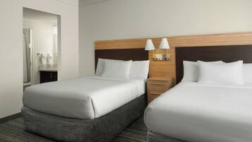 A hotel room with two beds, a wooden headboard, a nightstand, and a mirror.