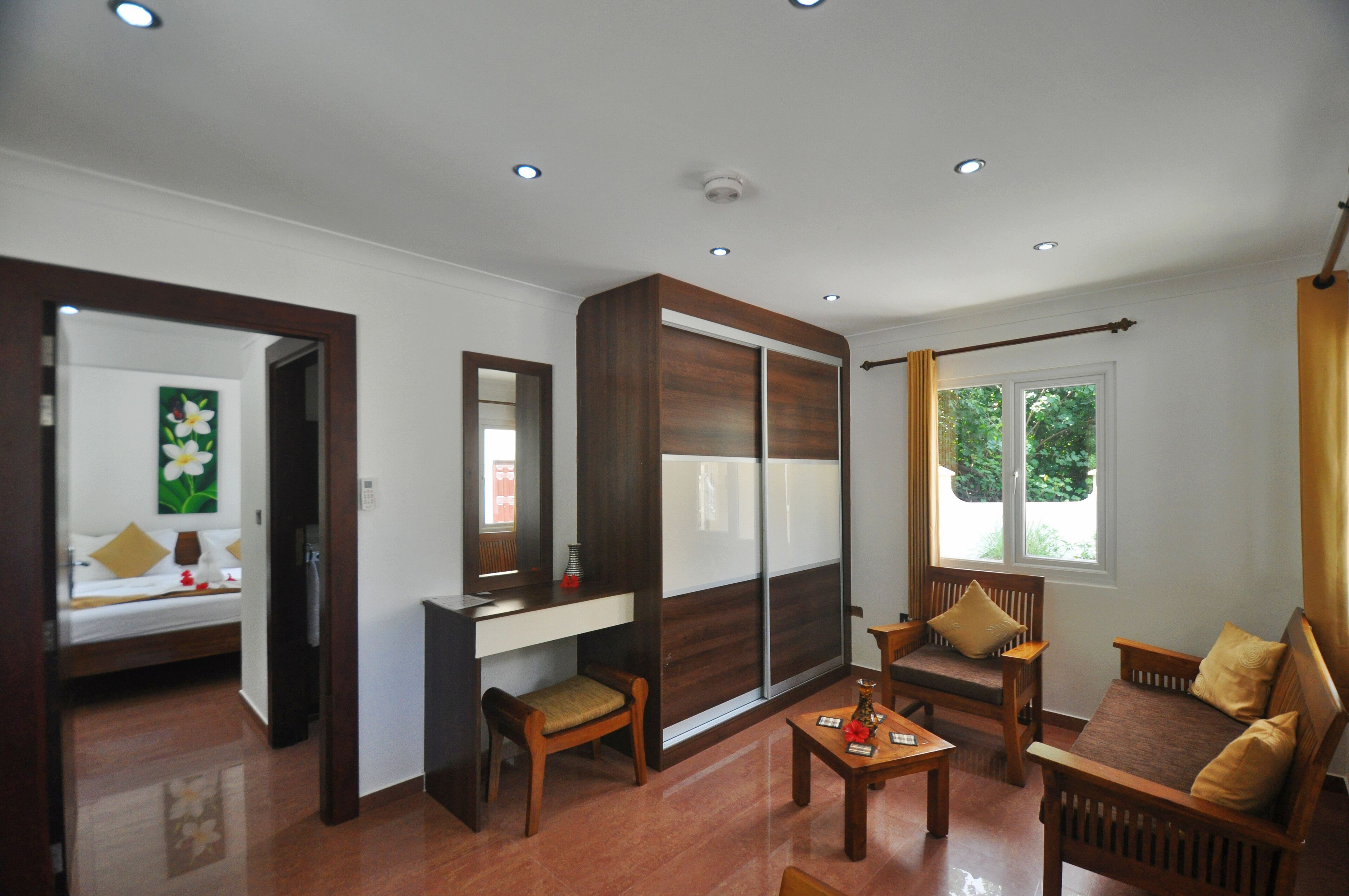A modern room with a wooden desk, two chairs, a sofa, and a large mirror.
