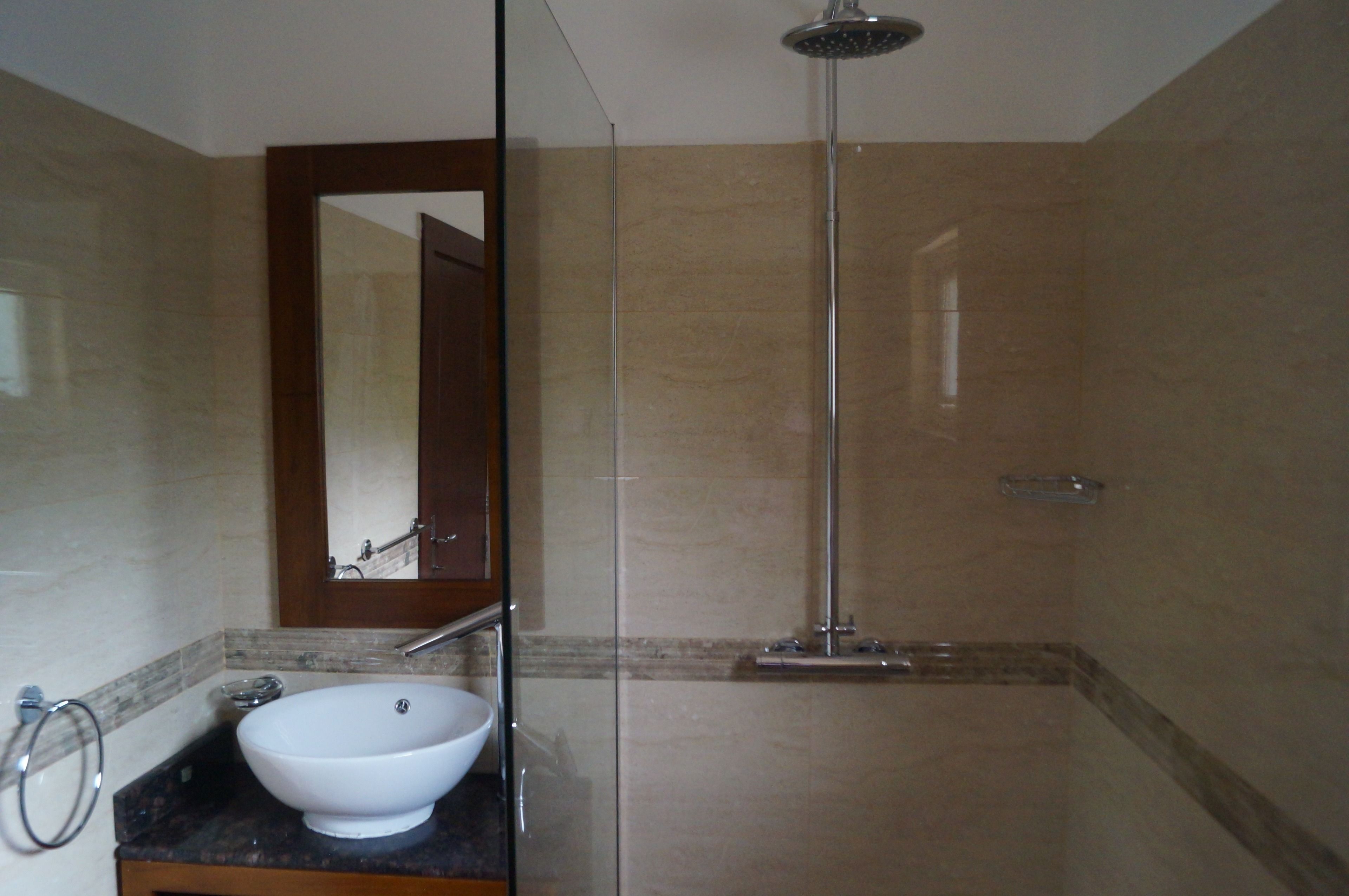 A bathroom with a glass-enclosed shower, a white sink, and a mirror.