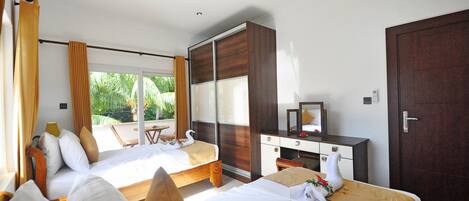 A hotel room with two beds, a desk, a mirror, and a wardrobe.