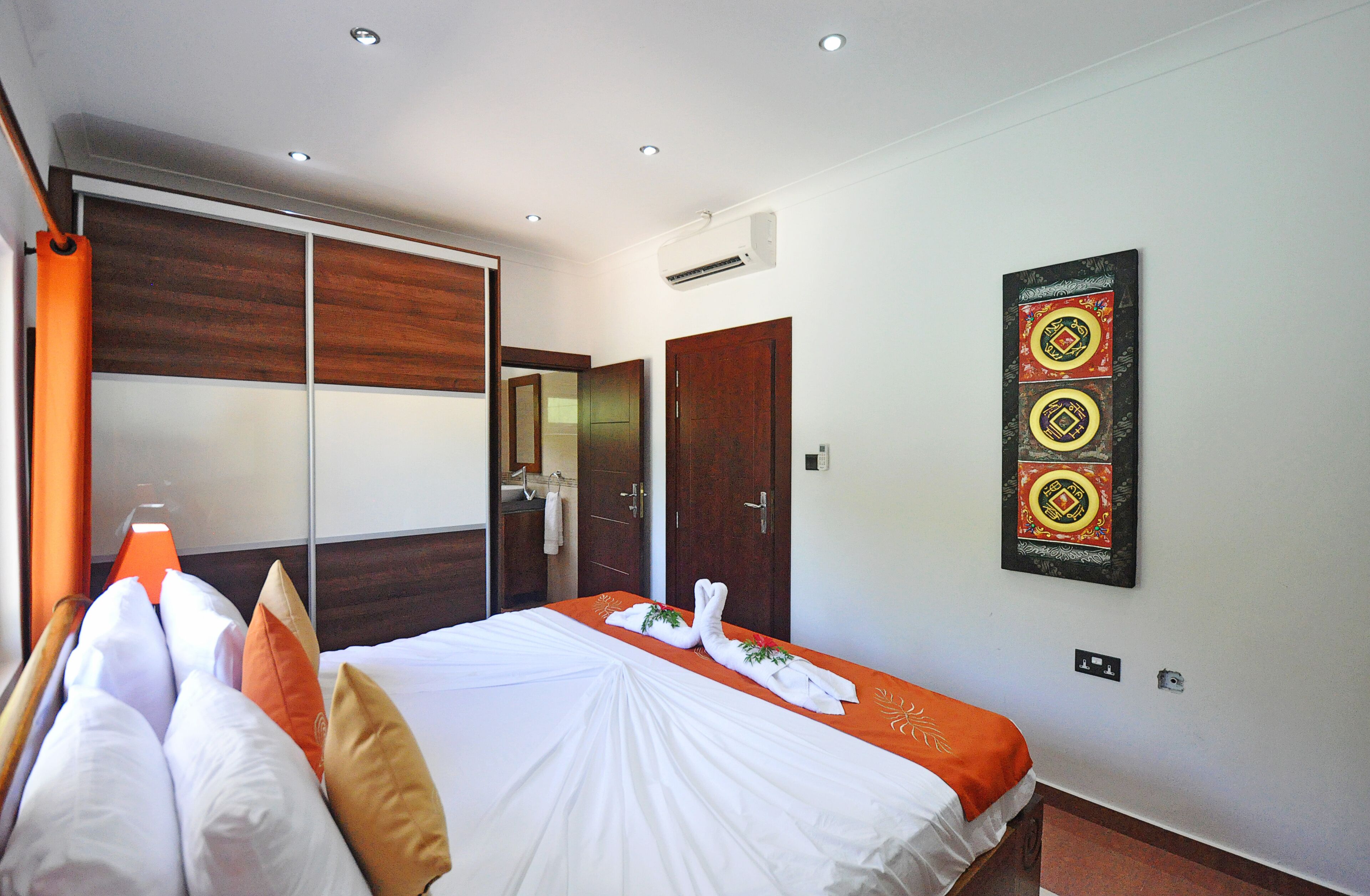 A hotel room with a bed, a wardrobe, a mirror, and a wall-mounted artwork.