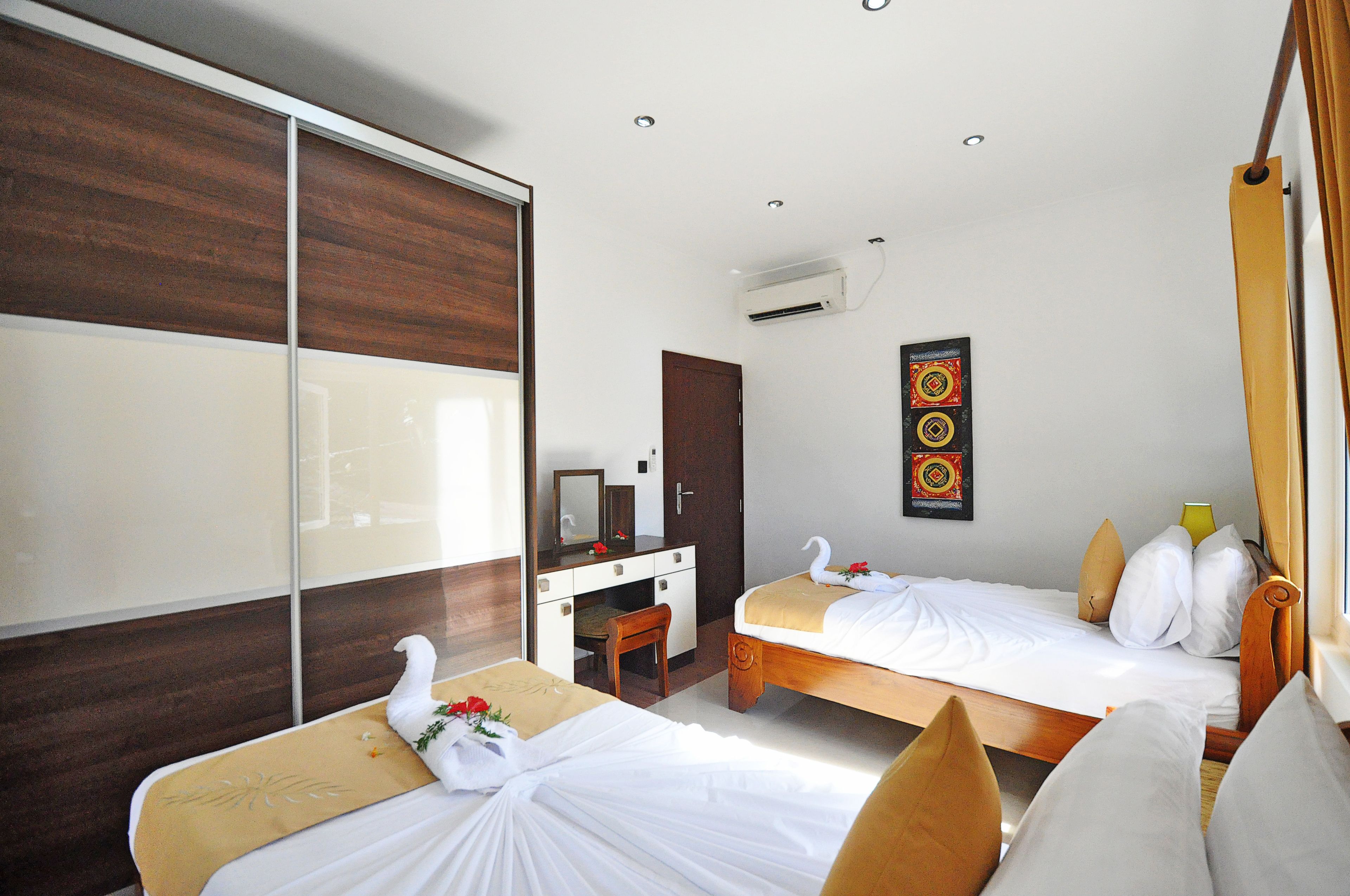 A hotel room with two beds, a desk, and a wardrobe.