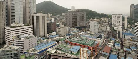 A dense urban area with high-rise buildings, a prominent hill with a tower, and a mix of commercial and residential structures.