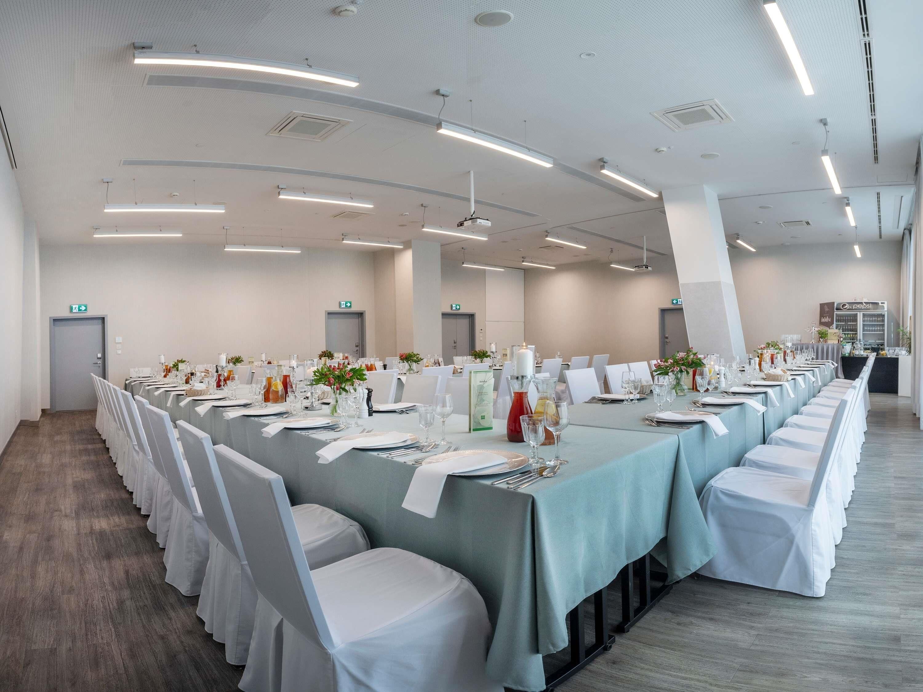 A conference room with a long table, white chairs, and overhead lighting.