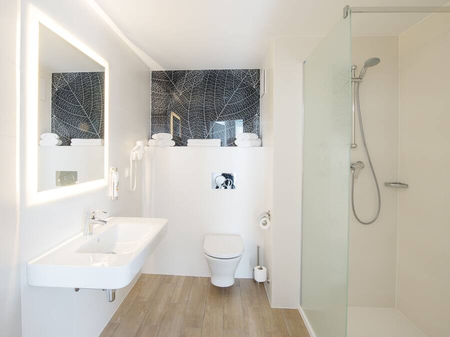 A modern bathroom with a white sink, toilet, and shower.