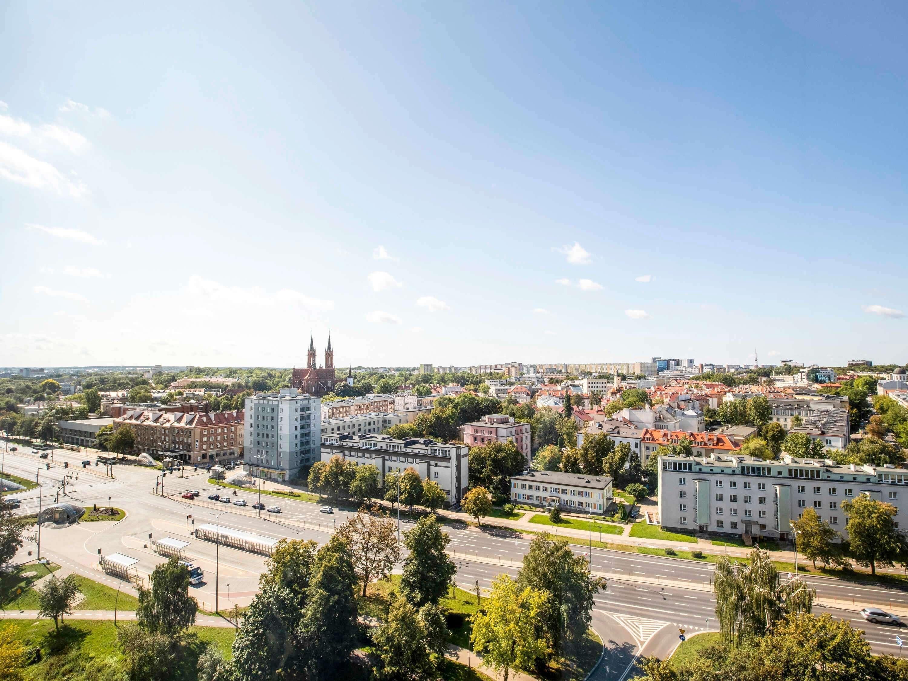 A cityscape with a prominent church, modern buildings, and a wide road.