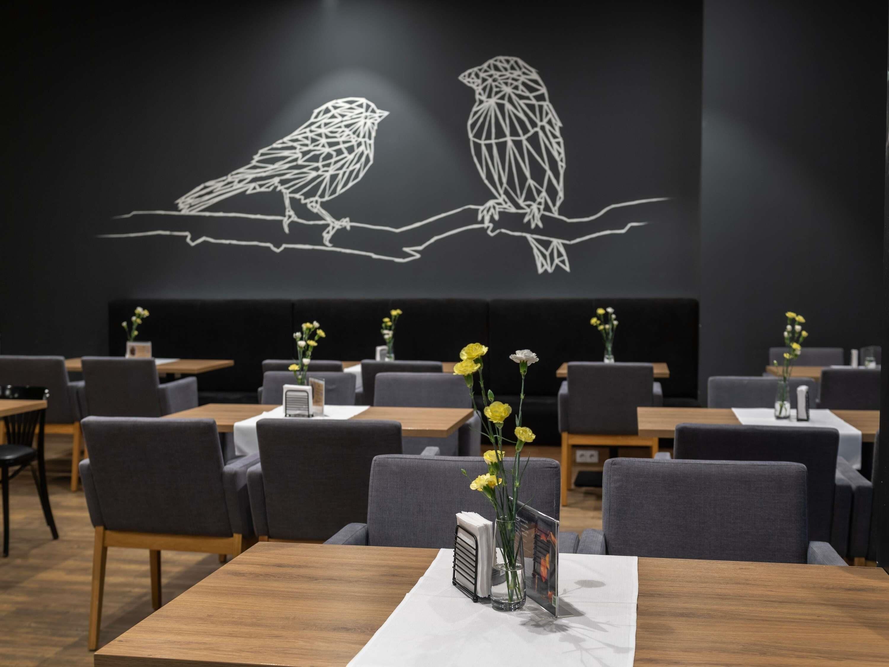 A restaurant with tables, chairs, and a wall art of owls.