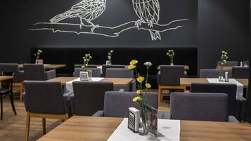 A restaurant with tables, chairs, and a wall art of owls.