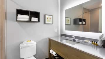 A modern bathroom with a toilet, a sink, a mirror, and two towel shelves.