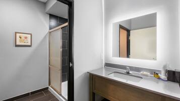 Un baño moderno con un espejo grande, un lavabo y una zona de ducha.