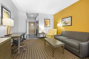 A hotel room with a desk, chair, sofa, and two framed artworks on the walls. - Best Western Plus Regency Park (Walker)
