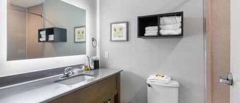 Un baño moderno con un espejo grande, un lavamanos, un inodoro y espacio para toallas.